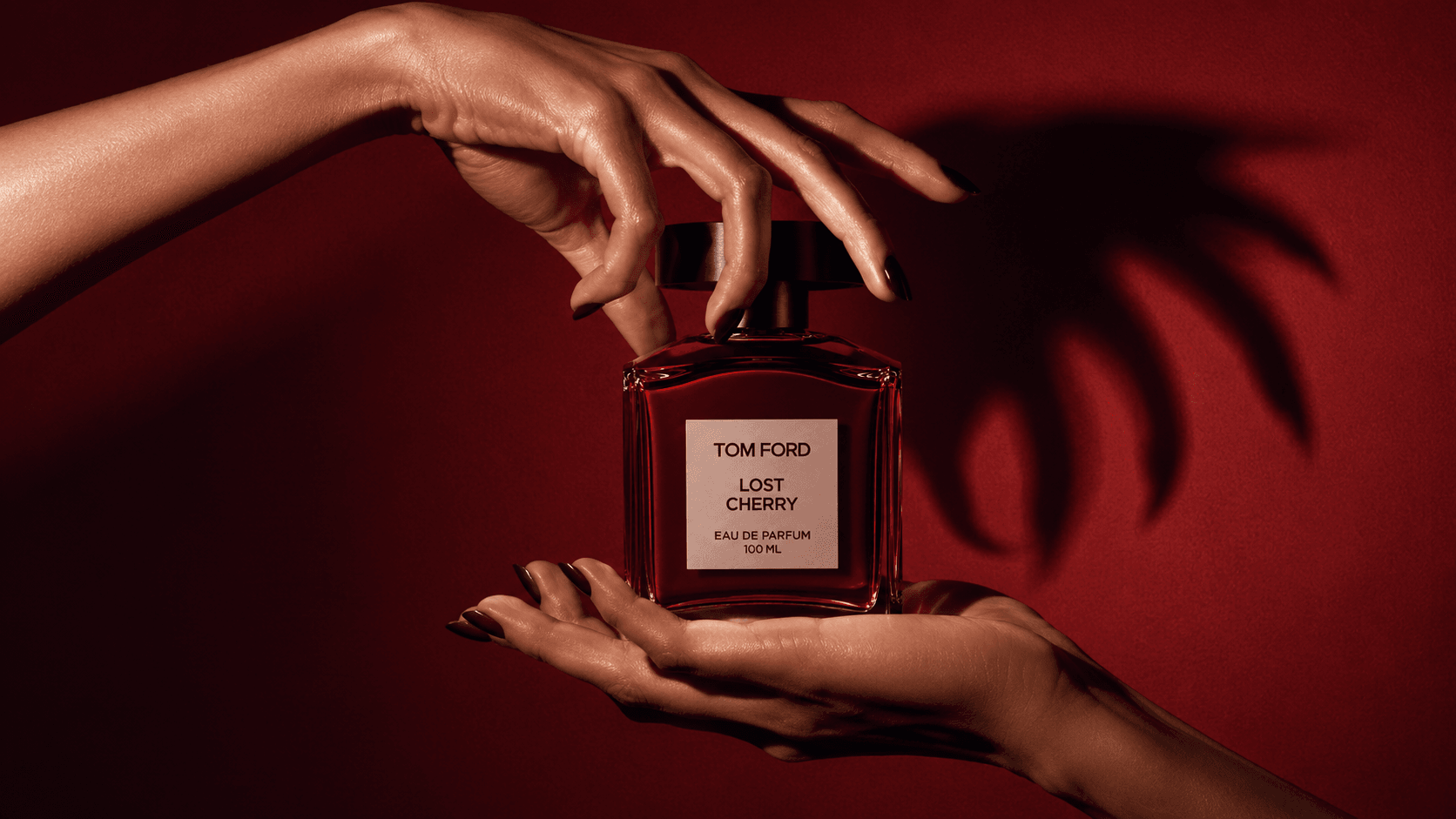 Hands holding the Lost Cherry bottle against red