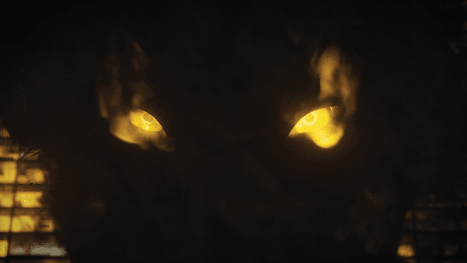 Two glowing yellow eyes in the dark above city lights.