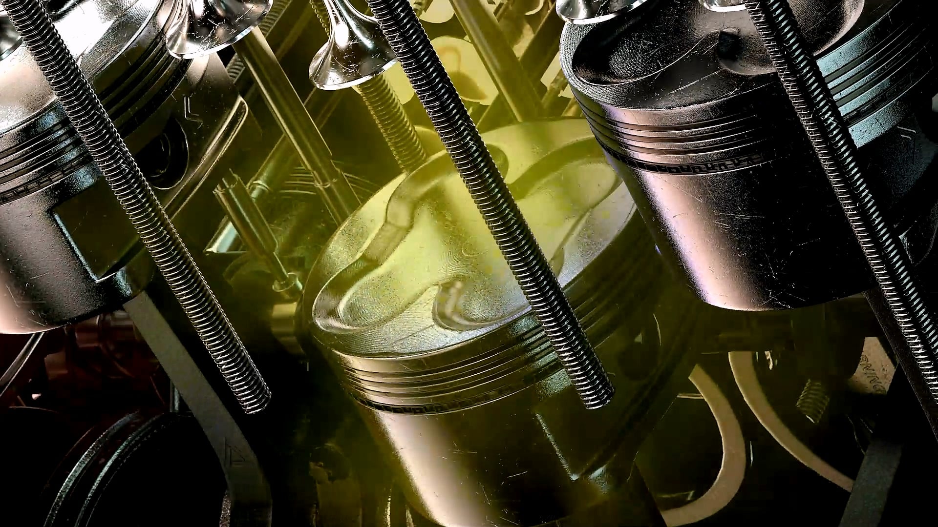 Close-up of engine pistons and connecting rods lit in yellow.